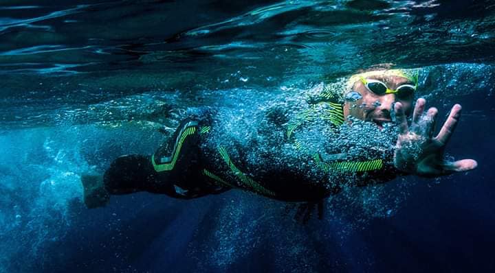 Nuotatore in acque libere visto sott'acqua