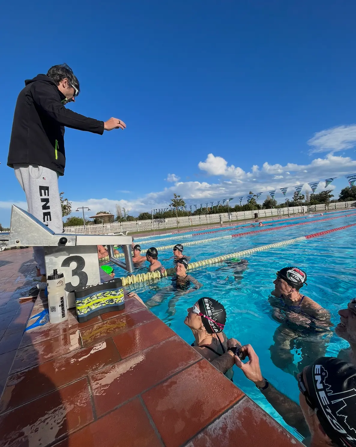 Coach Enea che istruisce gli atleti a bordo piscina